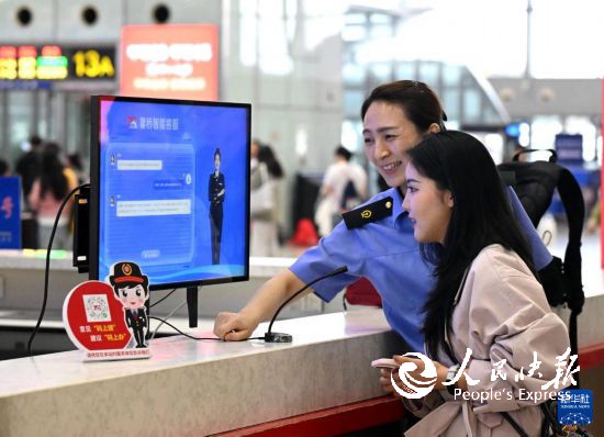 10月5日,在河北石家庄火车站候车大厅服务台,旅客向“AI智能客服机”问询旅行信息。 新华社发(陈其保摄)